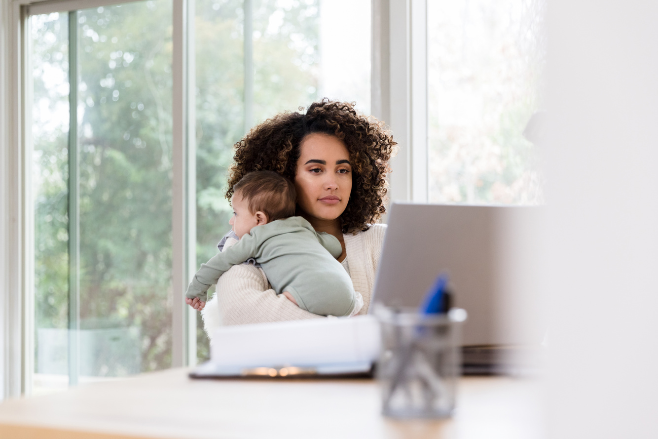 Stay-at-home mom holds baby while working remote